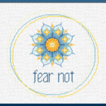 Intentional stitching with Karma Charms. This image is of the "Fear Not" design, which features a triple circle border in 3 colors plus a love mandala style lotus in bright blues and warm yellows. The words "fear not" appear at the bottom in small case.