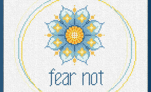 Fear Not: Stitching is Cheaper than Therapy, and this counted cross stitch design is good "stitch therapy." A mandala-style lotus in cheery blues and warm yellows floats off-center. Below it, the words "fear not" are stitched in blue. They appear to be floating within a border of three loosely overlapping circles.