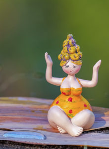 Change is good. In this image, a statuette of a curvy woman is seated in meditation. She's wearing a yellow monokini with pink flowers and her yellow hair is piled in rolls atop her head. From Grimalkin Crossing.