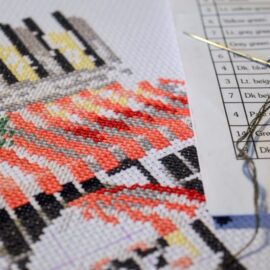 7 cross stitch hacks image. In it, a cross stitch projectis shown in progress, with part of a floss color key visible. From Grimalkin Crossing.