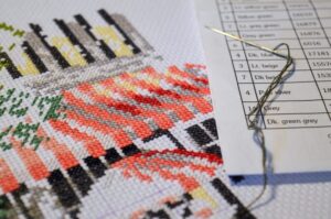 7 cross stitch hacks image. In it, a cross stitch projectis shown in progress, with part of a floss color key visible. From Grimalkin Crossing.