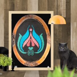 When you are bored, stitch a clit! This is a mockup photo for Clitarita, our best-selling design. It's shown in a bronzy-gold oval frame, which in turn is shown in a white pine frame. With a grimalkin beside it, of course! From Grimalkin Crossing.